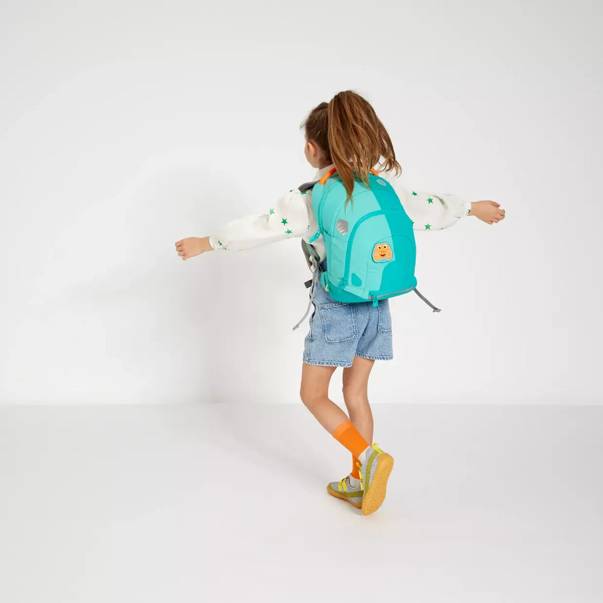 Child wearing the Affenzahn Daydreamer Crab Backpack in turquoise colors, showing ergonomic straps and spacious design for school or travel.