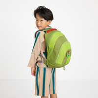 Boy carrying the Affenzahn Daydreamer Dinosaur Backpack, with visible side mesh pocket and colorful dragon badge on the green, durable fabric.