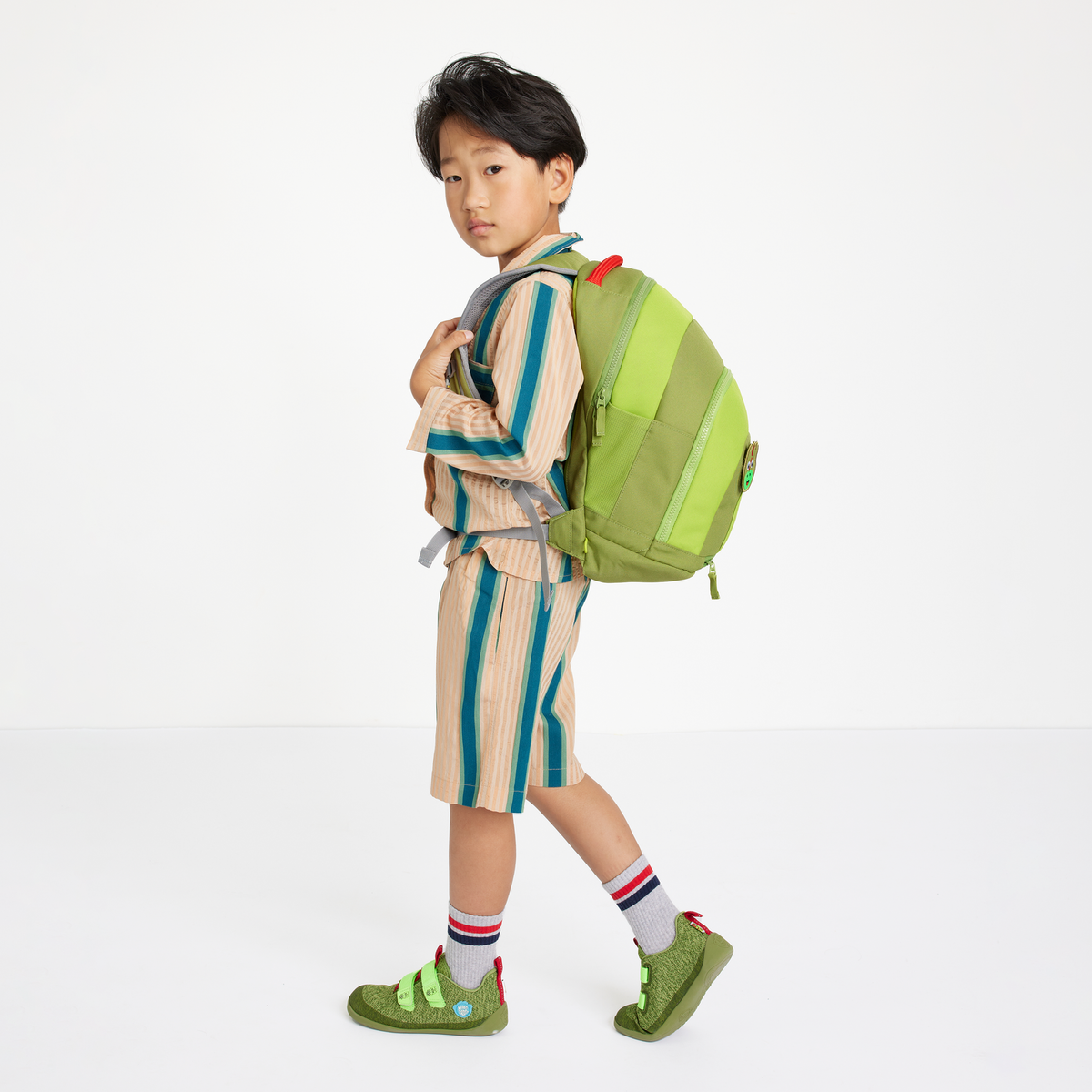 Child wearing the Affenzahn Daydreamer Dinosaur Backpack in green, showing ergonomic straps and spacious design for school or travel.