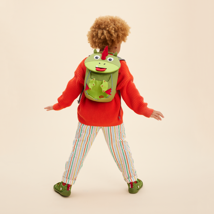 Affenzahn Small Friend Dinosaur backpack worn by a toddler, illustrating its size and fit.