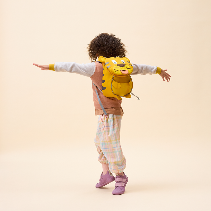 Affenzahn Small Friend Tiger backpack worn by a toddler, illustrating its size and fit.