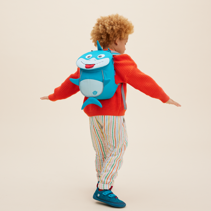 Affenzahn Small Friend Shark backpack worn by a toddler, illustrating its size and fit.